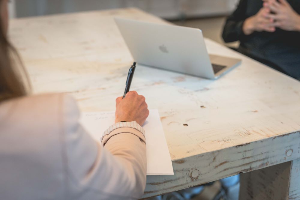 agiles_arbeiten Person macht sich Notizen während eines Meetings, symbolisiert strukturiertes und agiles Arbeiten im Team