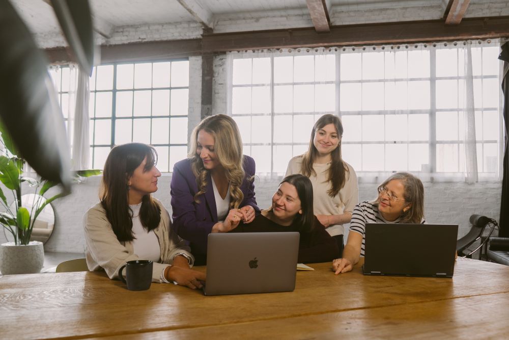 Gruppe von Frauen arbeitet gemeinsam am Laptop und symbolisiert Peer-Learning und kontinuierliche Führungsentwicklung