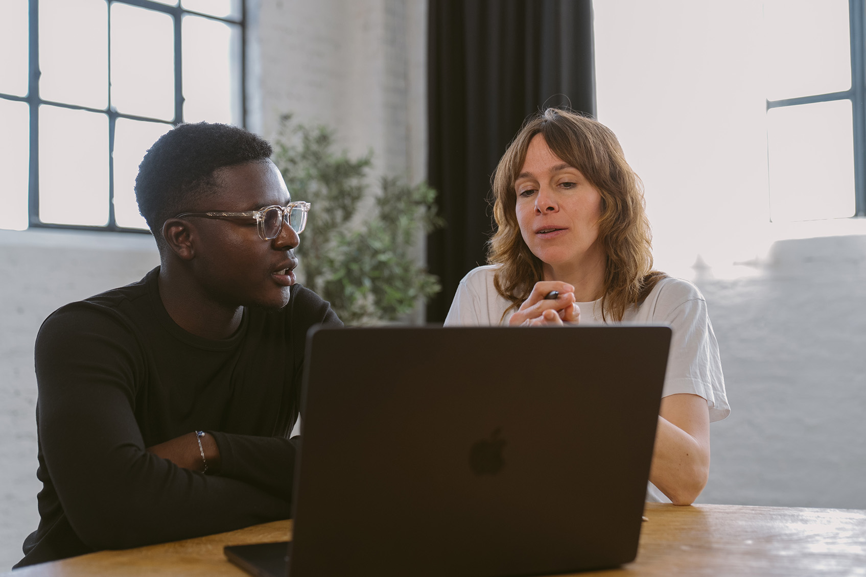 Zwei Personen sitzen vor Laptop